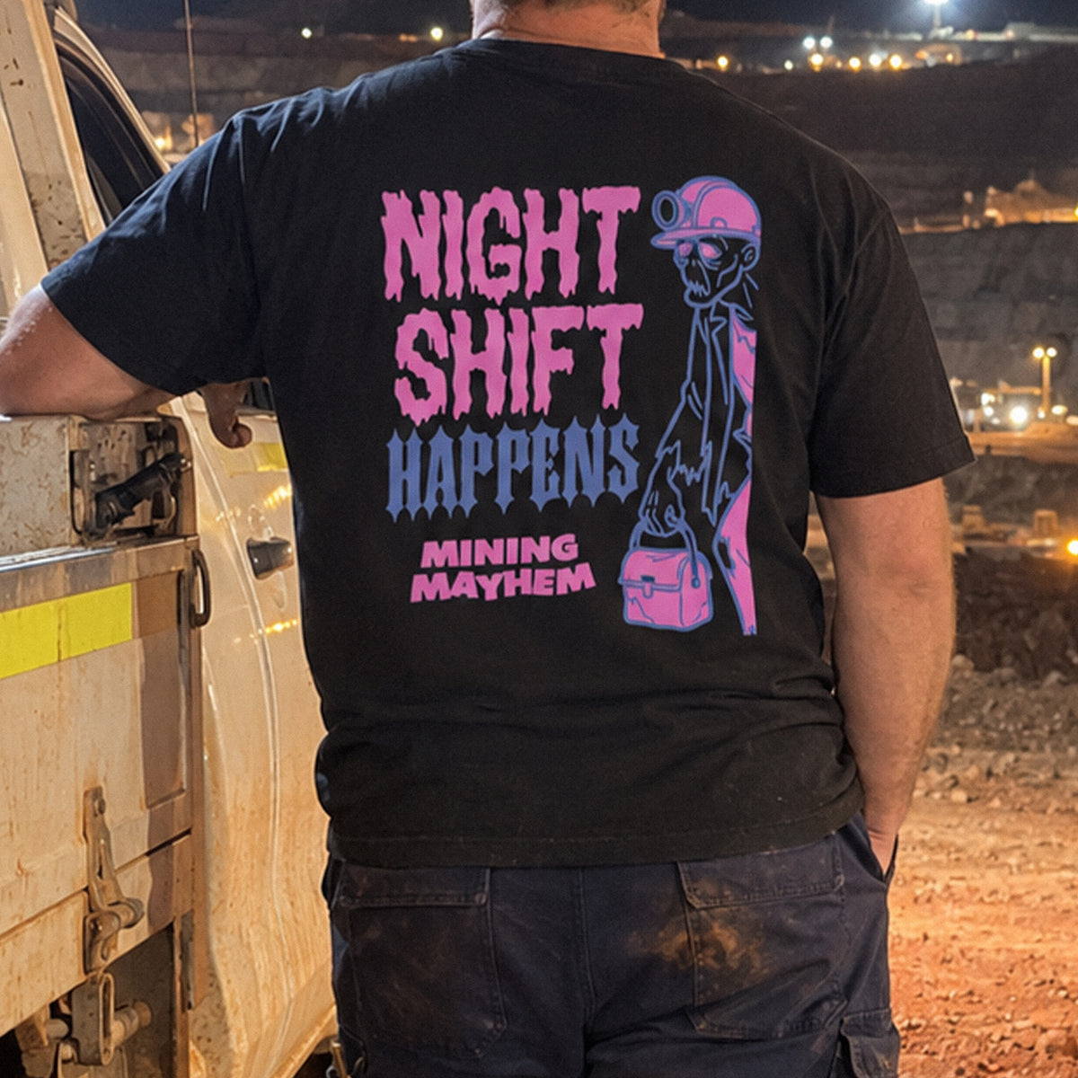 Miner wearing the black Night Shift Happens t-shirt on site at night, back print